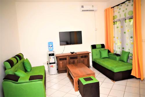 a living room with green furniture and a flat screen tv at V-Szameitat Homes in Diani Beach