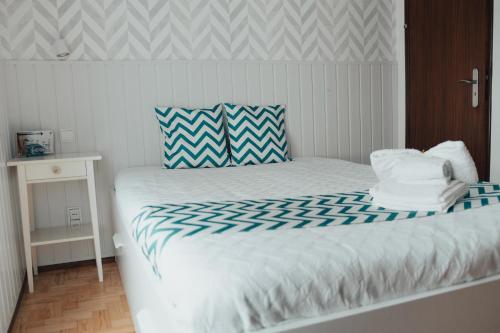 um quarto com uma cama branca com lençóis azuis e brancos em Camy House em Nazaré