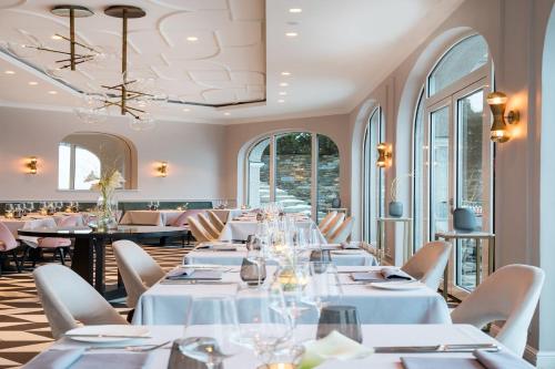 un ristorante con tavoli e sedie bianchi e finestre di Das Tegernsee a Tegernsee