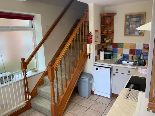 a kitchen with a staircase with a sink and a counter at Mallows Cottage in Sherborne