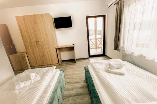 two beds in a room with a window at Pensiunea Balkan in Gornea