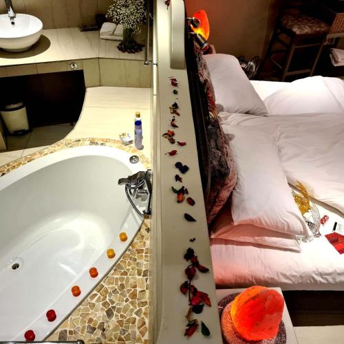 a bathroom with a bath tub and a bed at Crystal Lagoon Lodge in Langebaan