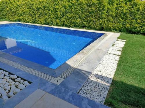 a blue swimming pool with rocks around it at Villa Leon in Reisdere