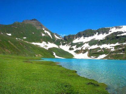 a body of water next to a snow covered mountain at Snow Land Guest House Naran in Nārān