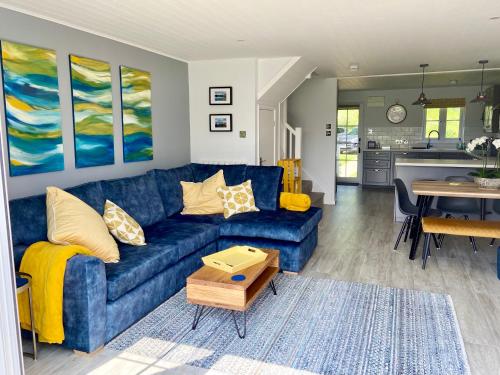a living room with a blue couch and a table at Lakehouse, 36 Isis Lake in Cirencester