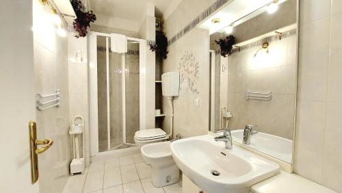 La salle de bains blanche est pourvue d'un lavabo et de toilettes. dans l'établissement Foscolo POOL apartment, à Bardolino