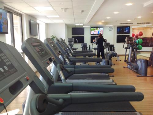 a gym with rows of tread machines and a man standing in the background at Bahi Ajman Palace Hotel in Ajman 