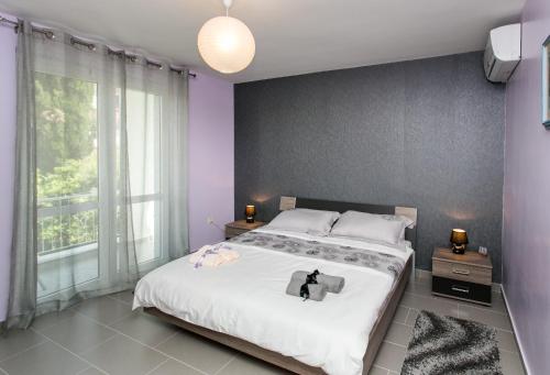 a bedroom with a large bed with purple walls at Lapad Bay Apartman - Black in Dubrovnik