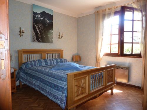 a bedroom with a bed with a blue comforter and a window at Appartement Rez de Jardin in Luz-Saint-Sauveur