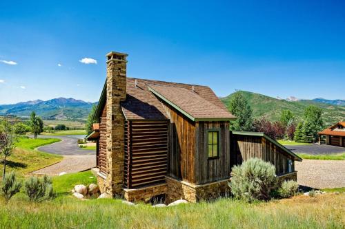 a log home with a chimney on a field at Chaparral Aspen Ranch Cabin in Woody Creek