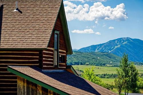 a house with a roof with mountains in the background at Chaparral Aspen Ranch Cabin in Woody Creek