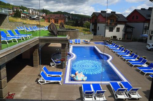 a swimming pool with blue chairs and a bunch at MARION SPA Hotel & Spa - RENOVATION - Rooms, SPA area, Swimming pool, Reception, Restaurant, Lounge Bar, Hookah bar, Children's room, Parking, SPA and Breakfast included in the price in Bukovel