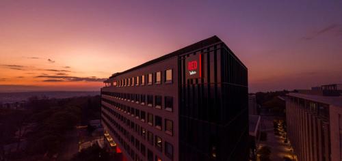 a building with a sign on the side of it at sunset at Radisson RED Hotel Johannesburg Rosebank in Johannesburg