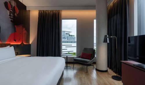 a hotel room with a bed and a chair and a window at Radisson RED Hotel Johannesburg Rosebank in Johannesburg
