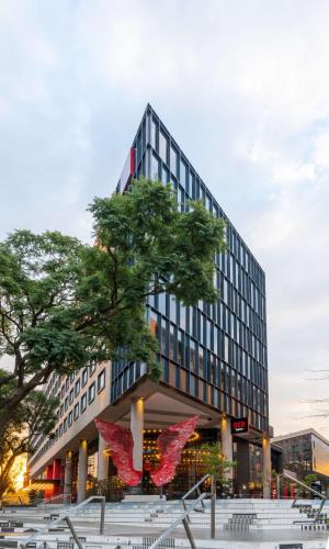 a building with a tree in front of it at Radisson RED Hotel Johannesburg Rosebank in Johannesburg