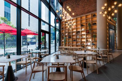 a restaurant with tables and chairs and large windows at Radisson RED Hotel Johannesburg Rosebank in Johannesburg