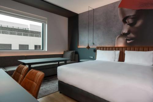 a hotel room with a bed and a table at Radisson RED Hotel Johannesburg Rosebank in Johannesburg