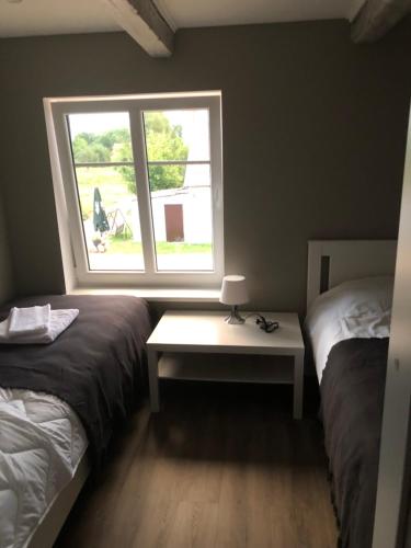 a room with two beds and a table with a window at Apartamentai Rusnės svečiams in Rusnė