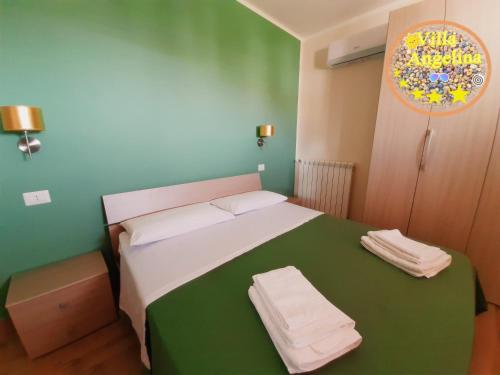 una camera da letto con un letto verde e bianco con asciugamani di Residenza Villa Angelina Tropea a Tropea