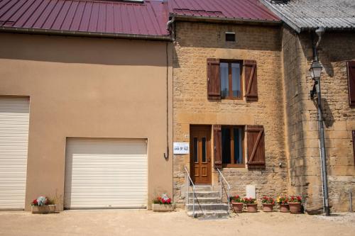 a brick house with two garage doors and flowers at "Chez la Joe" in Thélonne