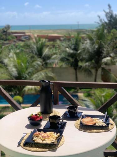 a table with a plate of food and a tea kettle at Apartamento Taiba Kite Beach Vista Mar in Taíba