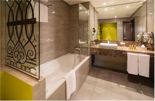 a bathroom with a tub and a shower and a sink at Mövenpick Hotel Casablanca in Casablanca