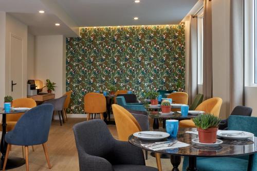 un restaurant avec des tables et des chaises et un mur vert dans l'établissement Hotel Apolonia Paris Montmartre; Sure Hotel Collection by Best Western, à Paris