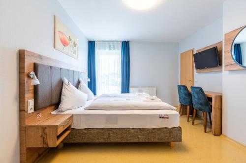 a bedroom with a bed and a desk and chairs at Hotel Arena in Cologne