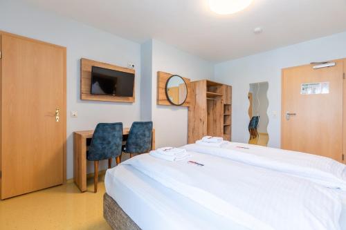 a bedroom with a large bed and two chairs at Hotel Arena in Cologne