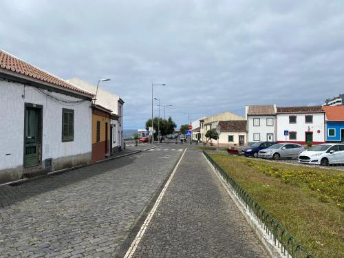 an empty street in a small town with cars parked at Casa das Ondas in Ribeira Grande