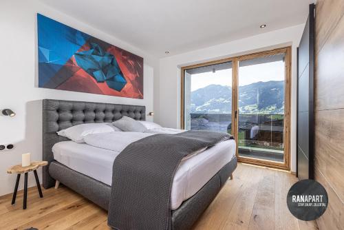 a bedroom with a large bed and a large window at RANAPART - Panoramawohnung Sonnenseite Zillertal in Hart im Zillertal