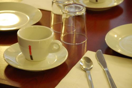 une table en bois avec une tasse et une assiette et une cuillère dans l'établissement Ruthenium Hotel, à Rodez