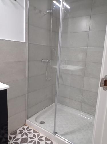 a shower with a glass door and a sink at Planeta Cadiz Hostel in Cádiz