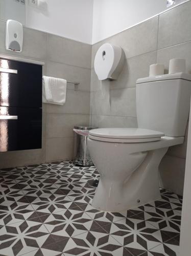 a bathroom with a toilet and a black and white floor at Planeta Cadiz Hostel in Cádiz