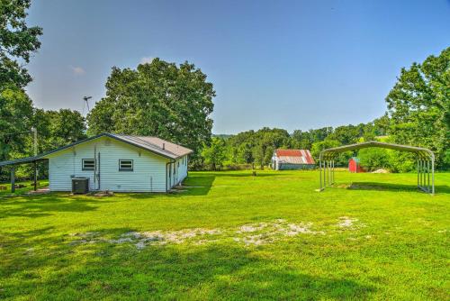 an old shed in a field with a playground at Quiet Country Home in Ava with Chic Interior! in Ava