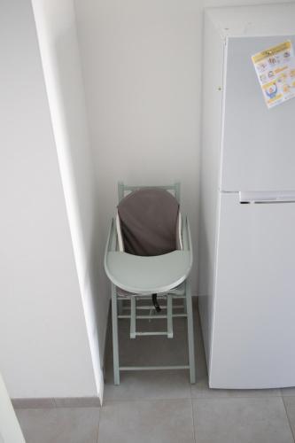 a white chair in a small room next to a refrigerator at "Chez la Joe" in Thélonne