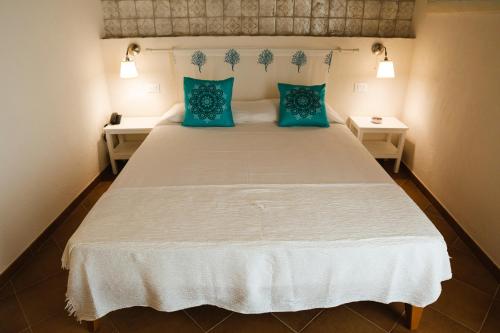 a bedroom with a large white bed with blue pillows at Casale La Macina - Hotel, Scopello in Scopello