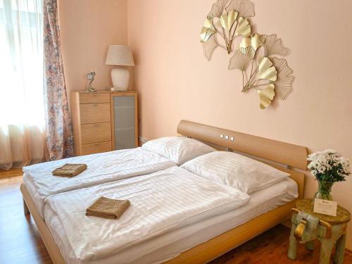 a bedroom with a bed with white sheets and flowers on the wall at Apartmá Marie 1880 in Karlovy Vary