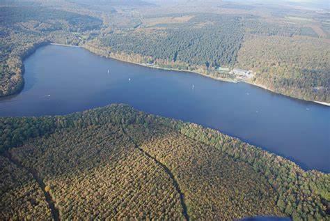 an aerial view of a lake with forests and a river at "Chez la Joe" in Thélonne