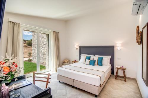 a bedroom with a bed and a large window at Cala Sinzias Resort in Castiadas