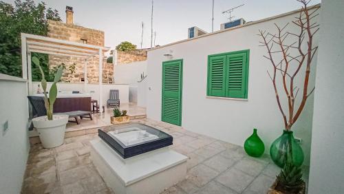 a patio with green doors and vases in front of a building at Borgo San Giovanni Luxury in Francavilla Fontana