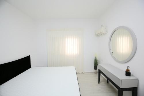 a white bedroom with a bed and a mirror at City center luxury apartment in Netanya in Netanya