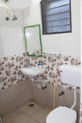 a bathroom with a sink and a toilet and a mirror at FriendlyStay at Madanandapuram in Chennai