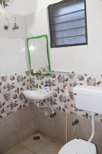 a bathroom with a sink and a toilet and a mirror at FriendlyStay at Madanandapuram in Chennai