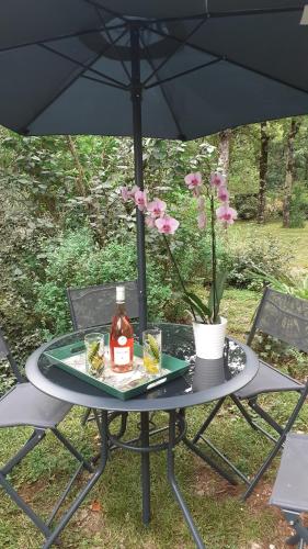 un tavolo con una bottiglia di alcol sotto ombrello di La Bergerie a Lagarrigue