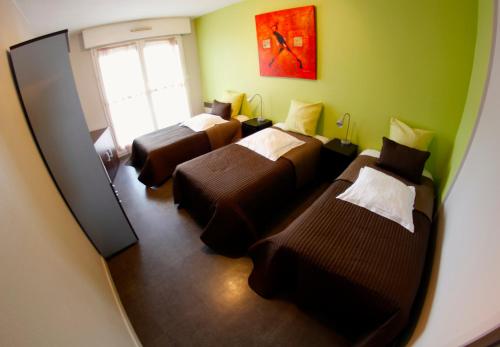 een kamer met 3 bedden en een spiegel bij Appart'hotel Les Palatines in Saint-Étienne