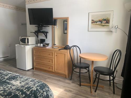 Habitación de hotel con mesa, sillas y TV en Motel Des Cascades en Baie-Saint-Paul