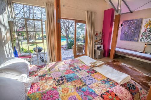 a bedroom with a bed with a colorful quilt on it at Aasvoelkrans Guest Farm in Montagu