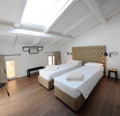 two beds in a room with white walls and wood floors at Opera 11 r&b in Parma