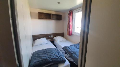 a small room with two beds and a window at Les Dunes de Contis in Saint-Julien-en-Born
